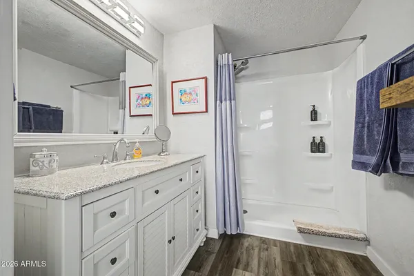 a bathroom with a granite countertop sink a mirror a shower and a bathtub