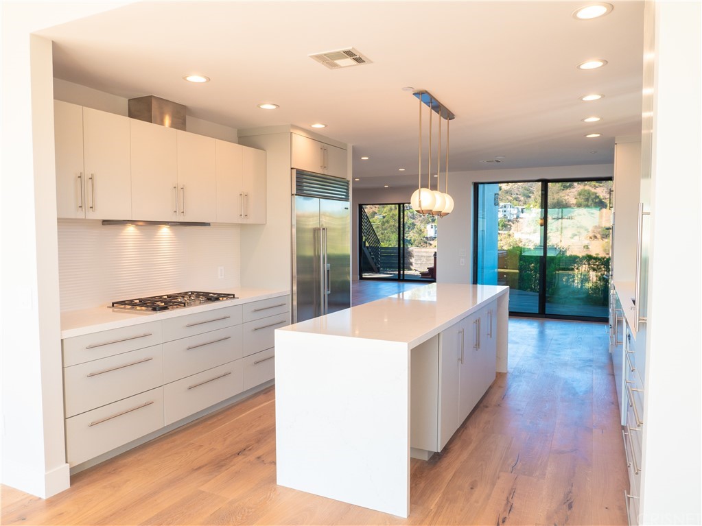 8184 Mannix Drive Los Angeles, CA 90046 - Photo 13 of 53 a large kitchen with kitchen island a stove a sink a refrigerator and a wooden floor