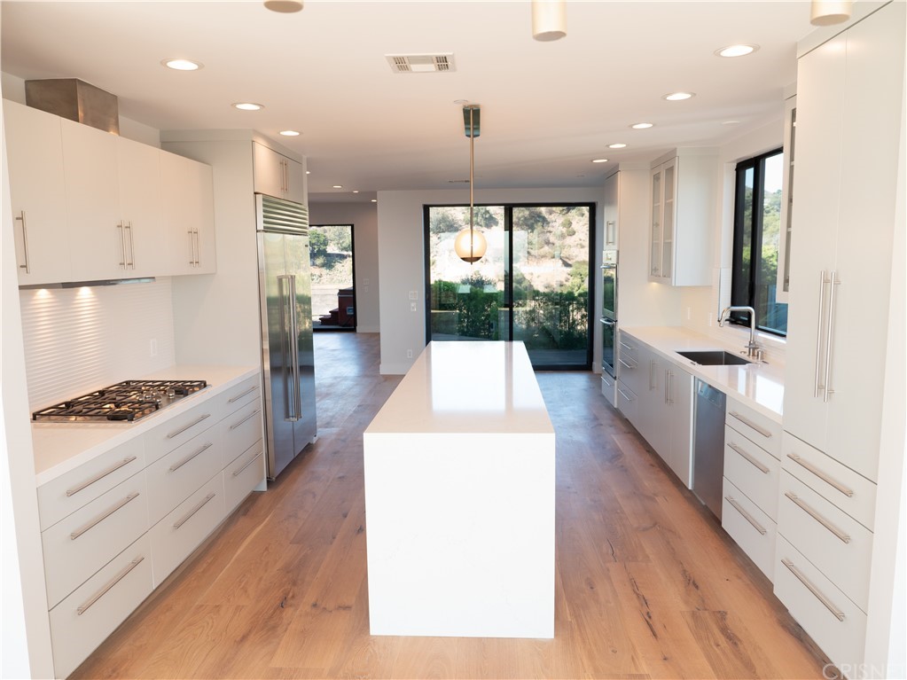 8184 Mannix Drive Los Angeles, CA 90046 - Photo 14 of 53 a large kitchen with stainless steel appliances kitchen island wooden floors wooden cabinets and a window