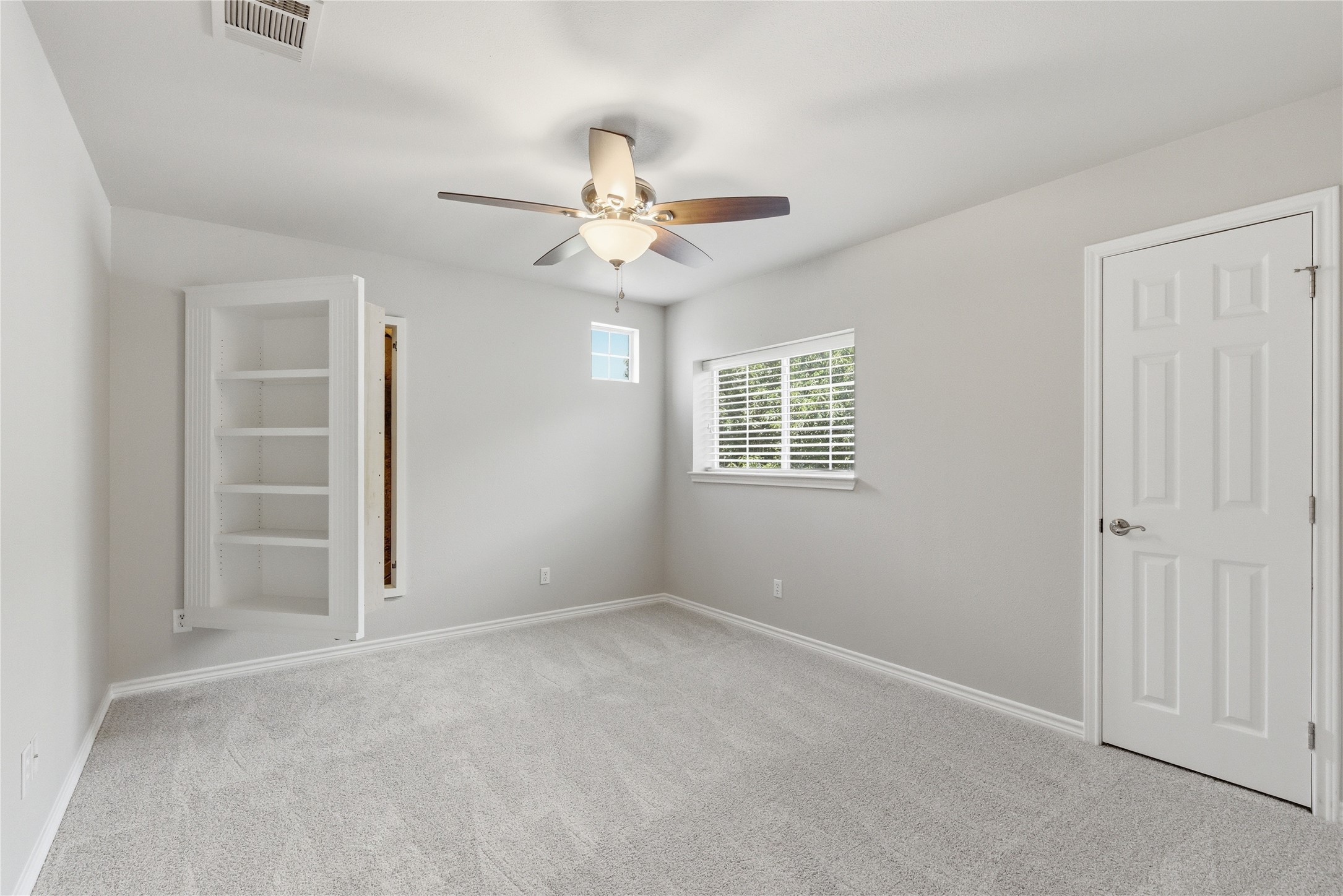 1204 Orlando Road Austin, TX 78733 - Photo 37 of 40 A well-lit room features a built-in bookshelf with a hidden door, offering both storage and a touch of intrigue.