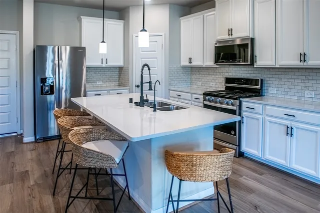 a kitchen with stainless steel appliances granite countertop a stove a refrigerator a sink a dining table and chairs with wooden floor