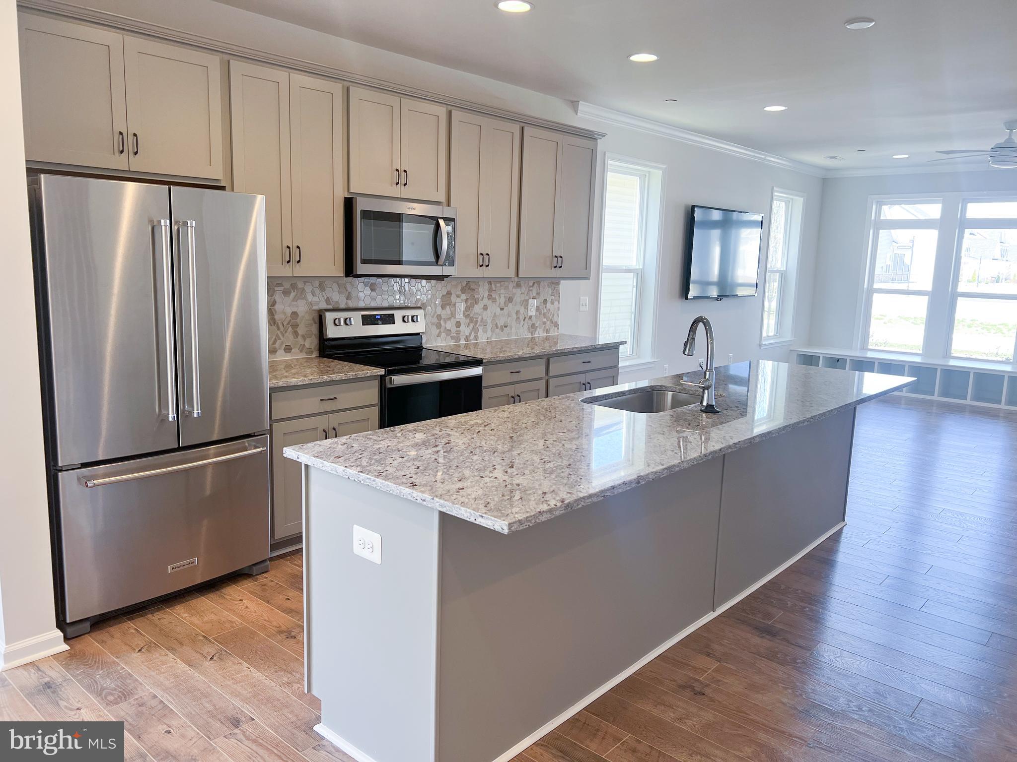 1015 Champlain Court Trappe, MD 21673 - Photo 5 of 38 a kitchen with granite countertop a refrigerator a sink a stove a microwave and wooden floor