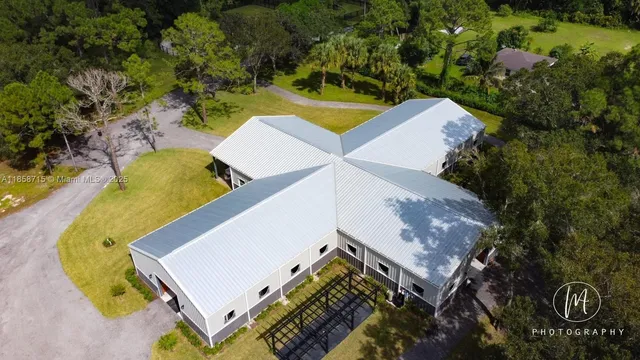 an aerial view of a house with swimming pool and large trees