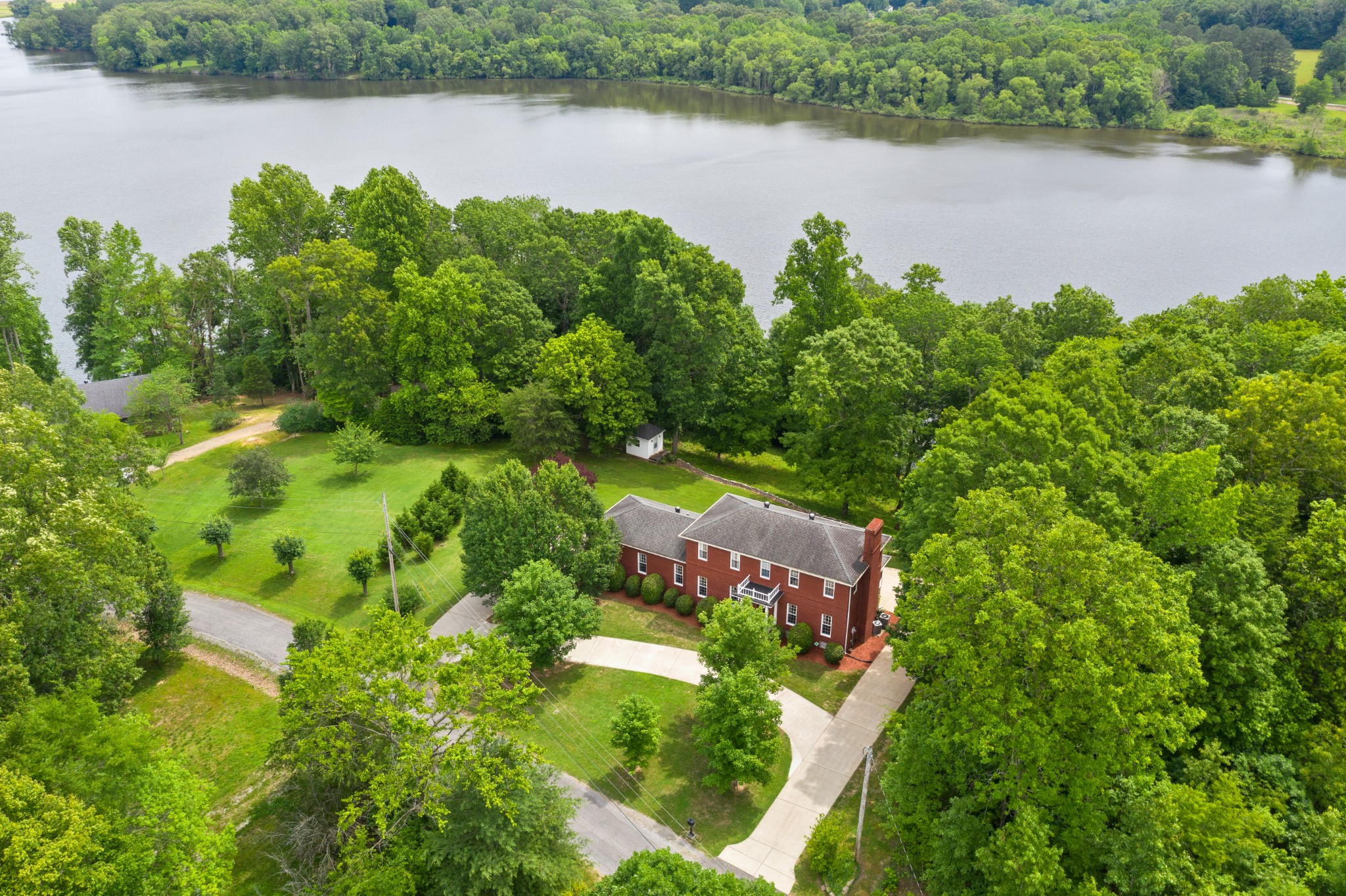 an aerial view of lake with residential house with outdoor space and trees around