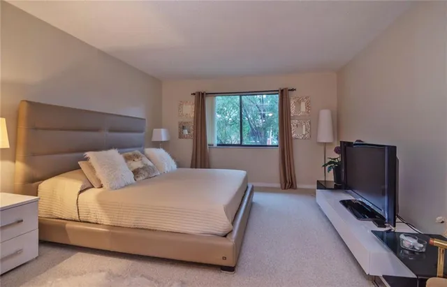 a bedroom with a bed flat screen tv and windows