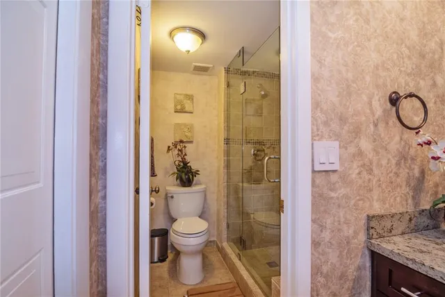 a bathroom with a granite countertop shower a toilet and a sink