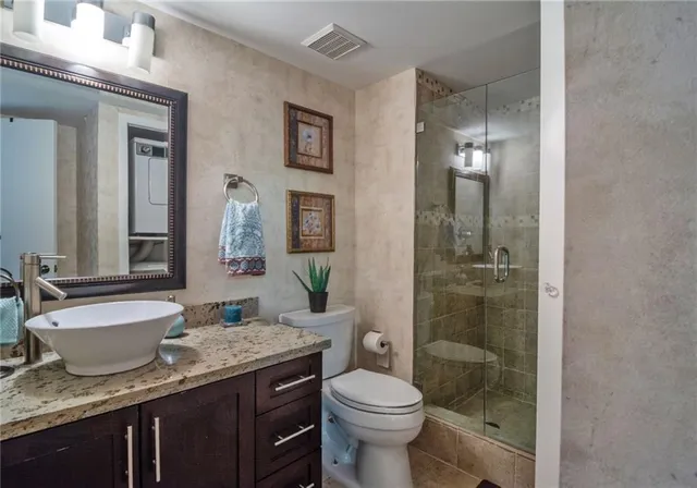 a bathroom with a granite countertop sink a toilet a mirror and shower