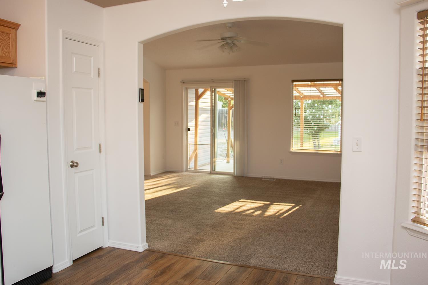 16559 Bayou Way Caldwell, ID 83607 - Photo 9 of 20 Arched doorway leading to a carpeted living space with a sliding glass door, an additional window, and a ceiling fan