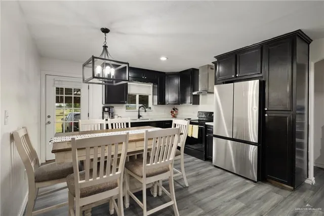 a kitchen with stainless steel appliances a refrigerator a stove a sink a dining table and chairs