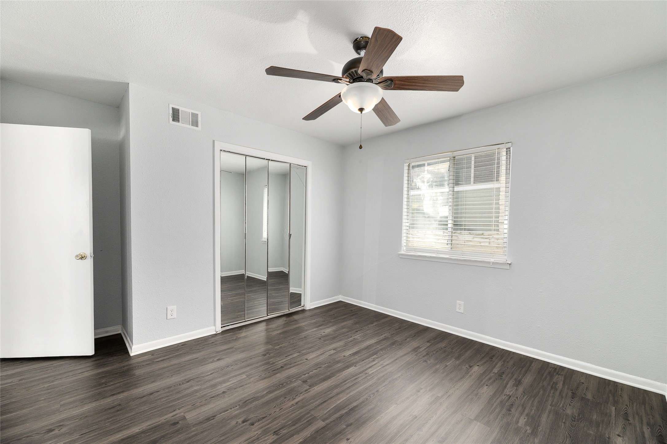 2408 Longview Street, Unit 113 Austin, TX 78705 - Photo 17 of 23 Unfurnished bedroom featuring dark wood-type flooring, a closet, and a ceiling fan