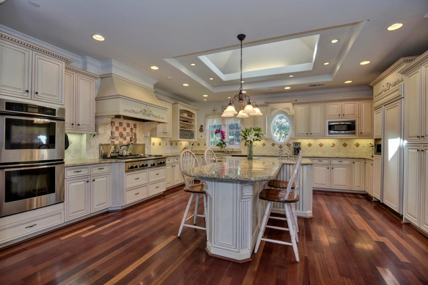 22219 Summit Road Los Gatos, CA 95033 - Photo 10 of 34 a kitchen with stainless steel appliances a dining table chairs stove and white cabinets