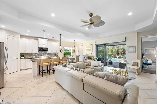 a living room with stainless steel appliances kitchen island furniture and a large window