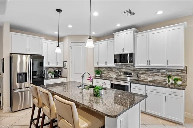 a kitchen with stainless steel appliances granite countertop a stove top oven a refrigerator a sink and a center island