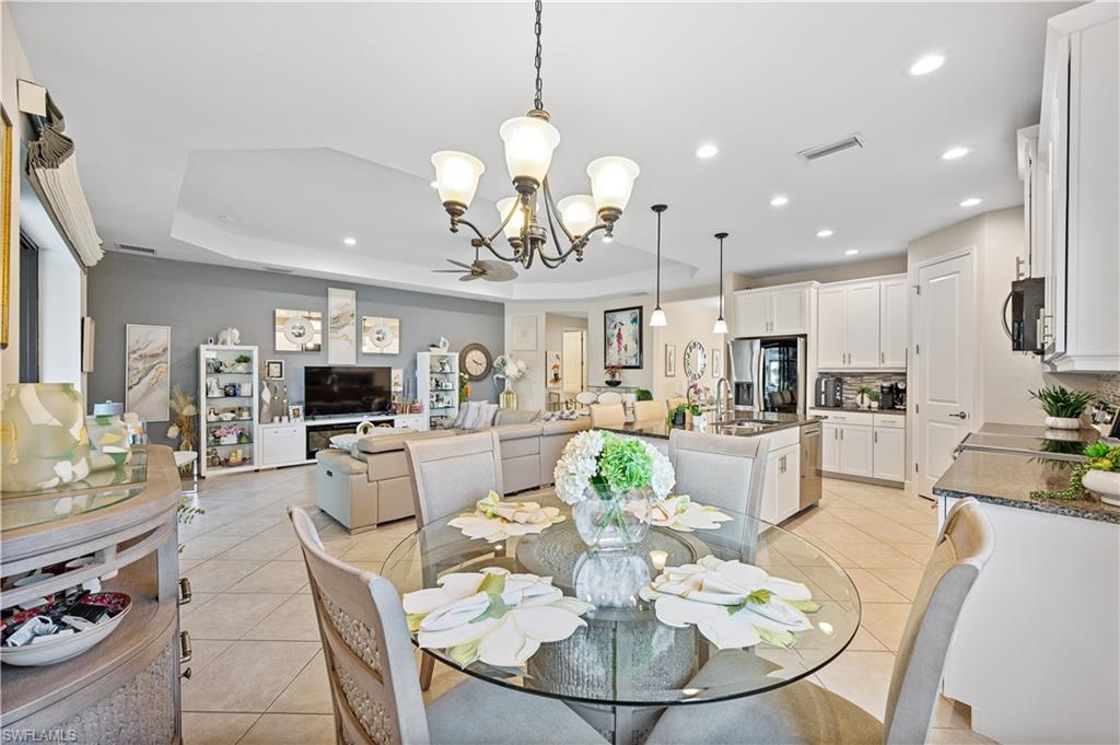 3585 Canopy Circle Naples, FL 34120 - Photo 29 of 46 a view of a dining room and livingroom with furniture a rug a fireplace and a chandelier