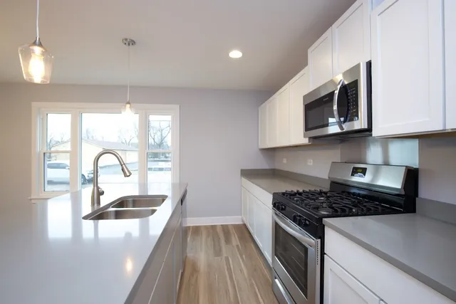 a kitchen with granite countertop a stove a sink and a microwave