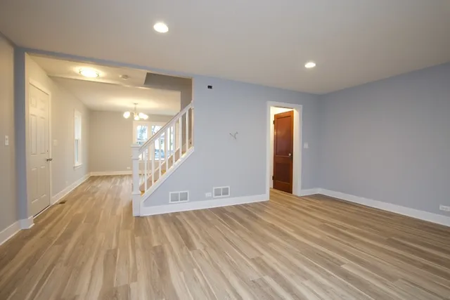 a view of an empty room with wooden floor and a bathroom