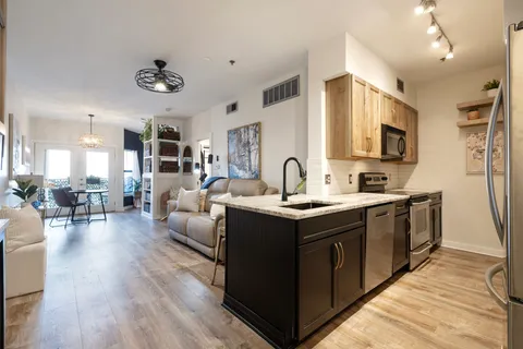 a large white kitchen with stainless steel appliances granite countertop a lot of counter space and wooden floors