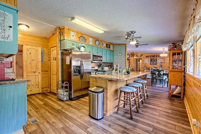 a kitchen with stainless steel appliances granite countertop a refrigerator a stove top oven and a dining table with wooden floor