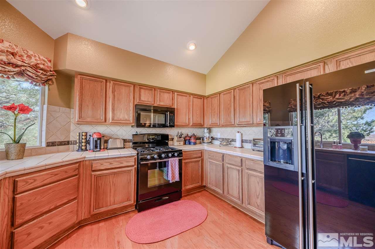 14225 Ghost Rider Drive Reno, NV 89511 - Photo 7 of 24 a kitchen with stainless steel appliances granite countertop a stove top oven a sink dishwasher a dining table and chairs with wooden floor