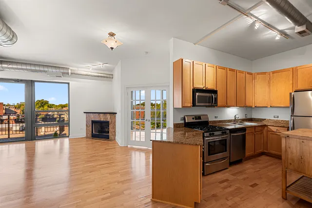 a kitchen with stainless steel appliances granite countertop a stove top oven a sink dishwasher a dining table and chairs with wooden floor