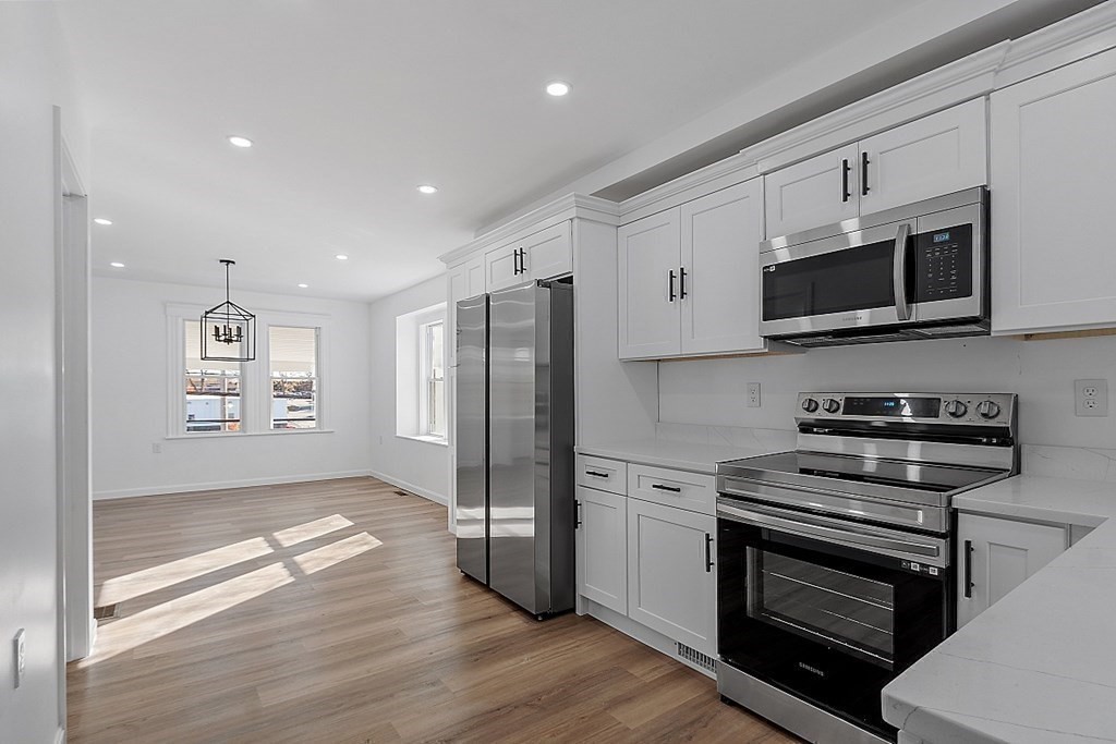 a kitchen with stainless steel appliances a stove a microwave and a hard wood floors