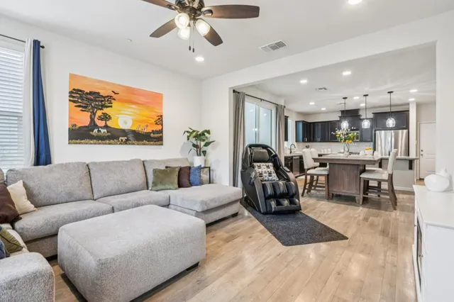 a living room with furniture kitchen view and a chandelier