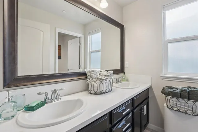 a bathroom with double vanity sinks a mirror and a window