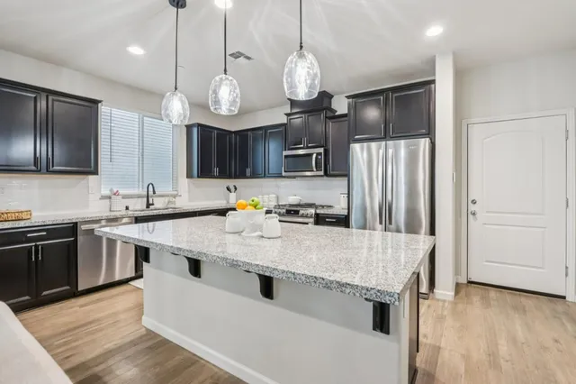 a large kitchen with granite countertop a sink stainless steel appliances and cabinets