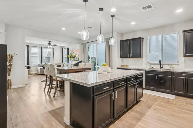 a kitchen with stainless steel appliances granite countertop a stove a sink dishwasher a refrigerator and a dining table with wooden floor