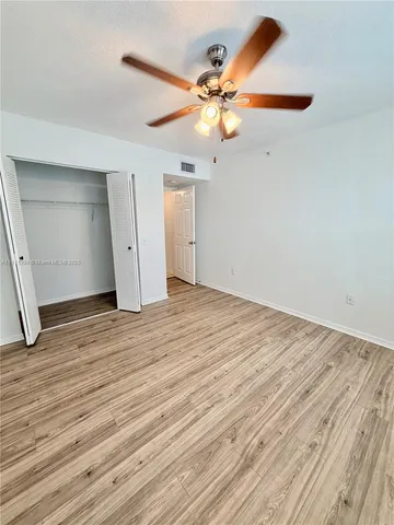 an empty room with wooden floor fan and windows