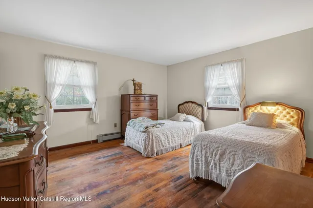 a bedroom with two beds and a potted plant next to a window