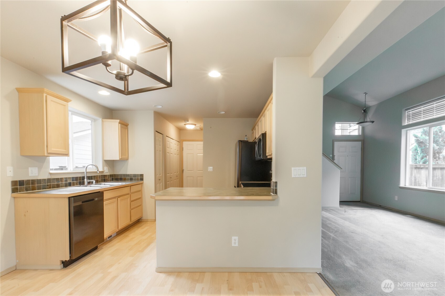 22463 Southeast 244th Street Maple Valley, WA 98038 - Photo 4 of 26 a view of a kitchen with kitchen island a stove a sink a refrigerator and a view of living room
