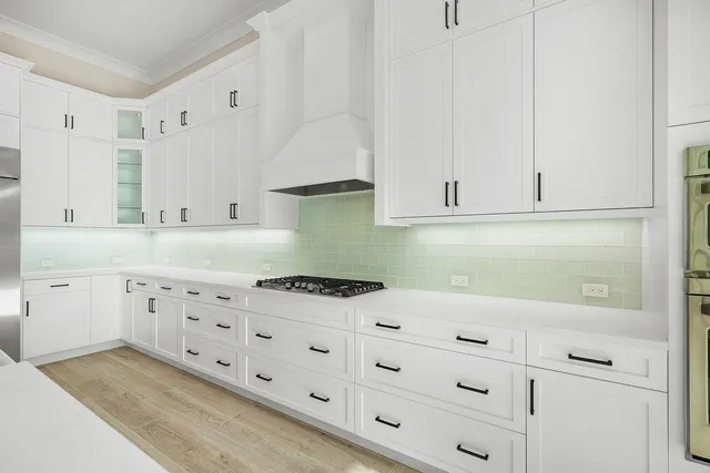 a large white kitchen with stainless steel appliances granite countertop a stove a sink and a refrigerator