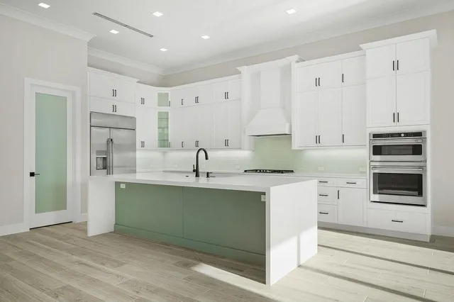 a kitchen with stainless steel appliances a sink cabinets and a wooden floor