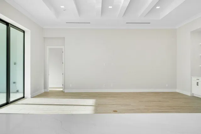 a view of a hallway with wooden floor and a bathroom