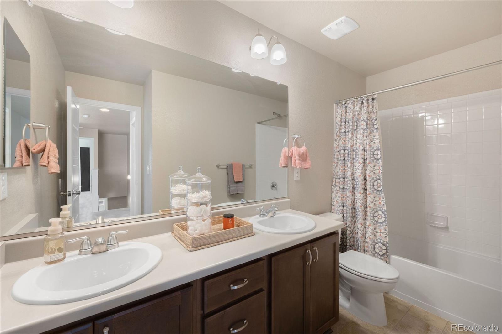 8809 Foxfire Street Firestone, CO 80504 - Photo 16 of 32 a bathroom with a double vanity sink toilet and a mirror