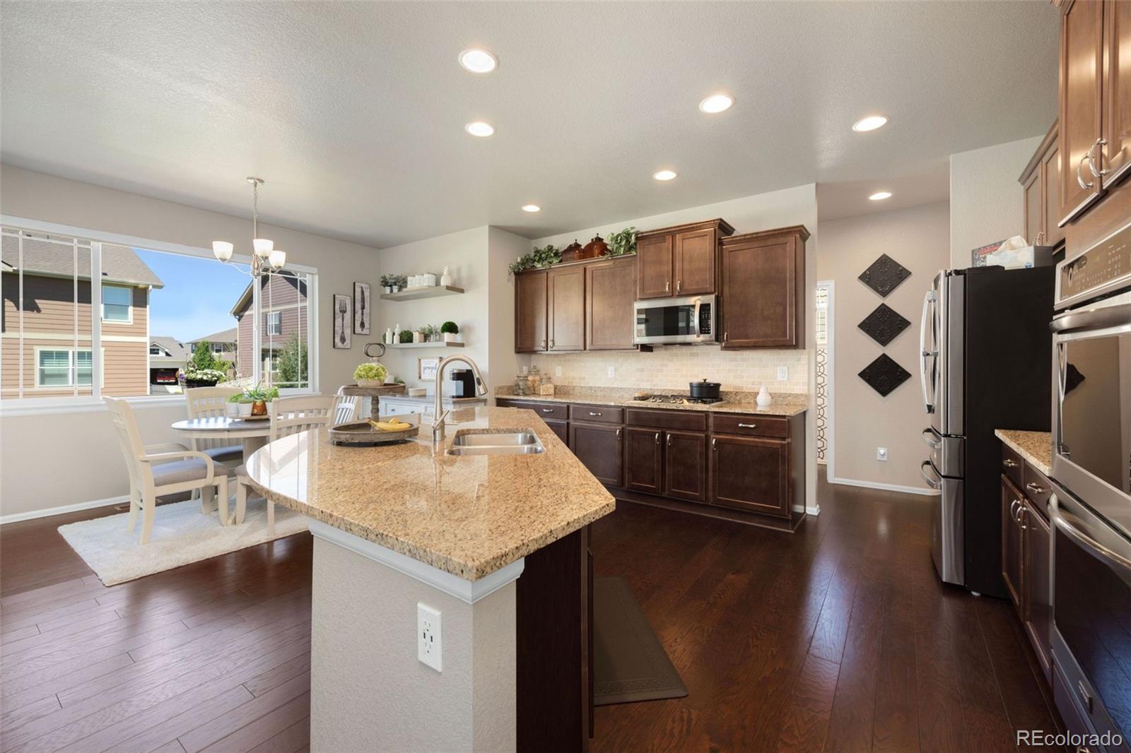 8809 Foxfire Street Firestone, CO 80504 - Photo 10 of 32 a kitchen with stainless steel appliances kitchen island granite countertop a sink refrigerator and cabinets