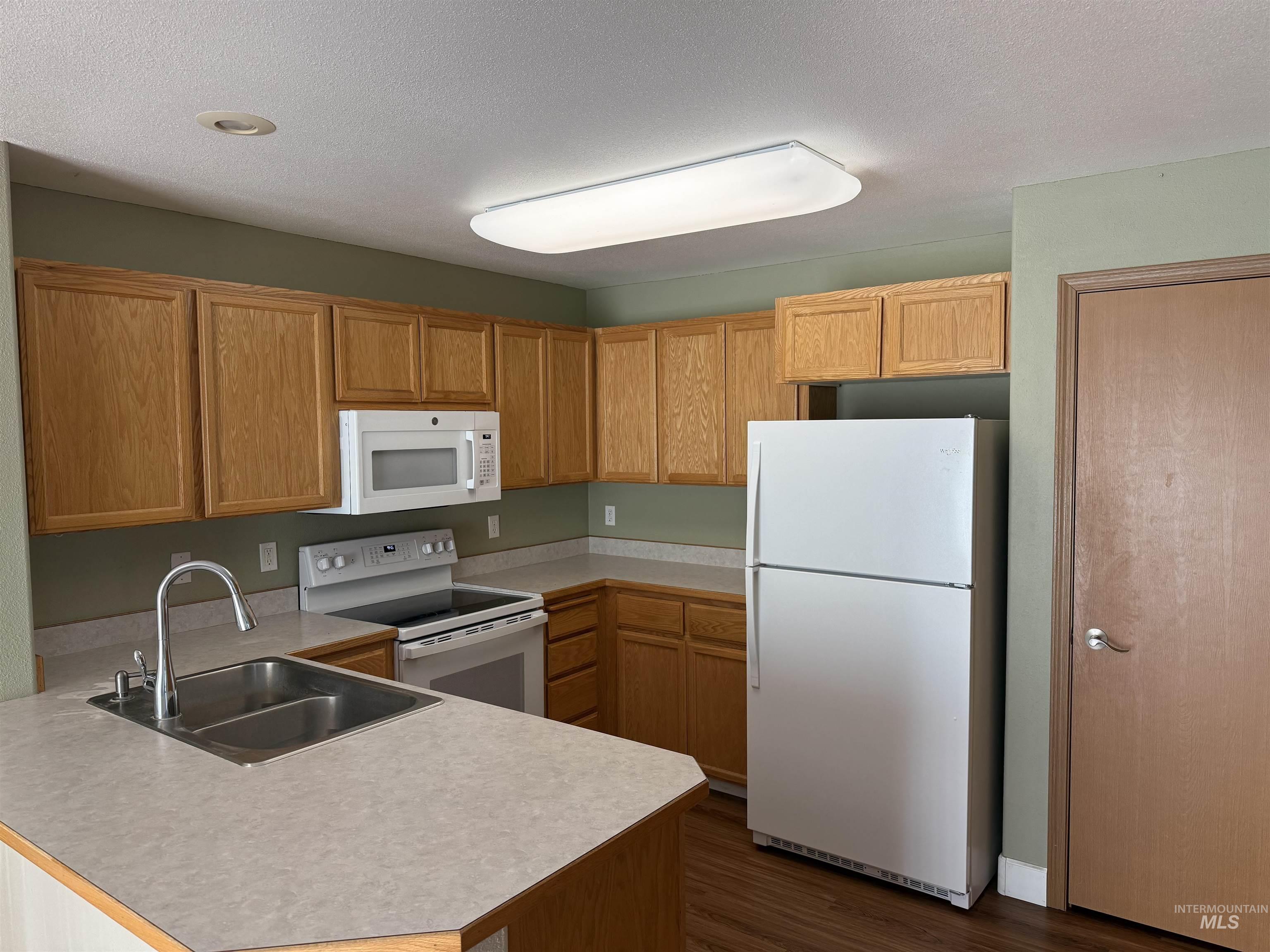 257 Pintail Lane Moscow, ID 83843 - Photo 5 of 28 Kitchen with light countertops, white appliances, dark wood finished floors, wood finish cabinetry, and a peninsula