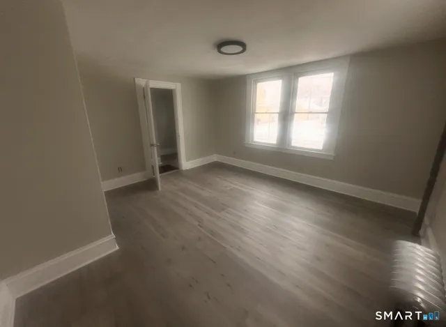 a view of an empty room with wooden floor and window