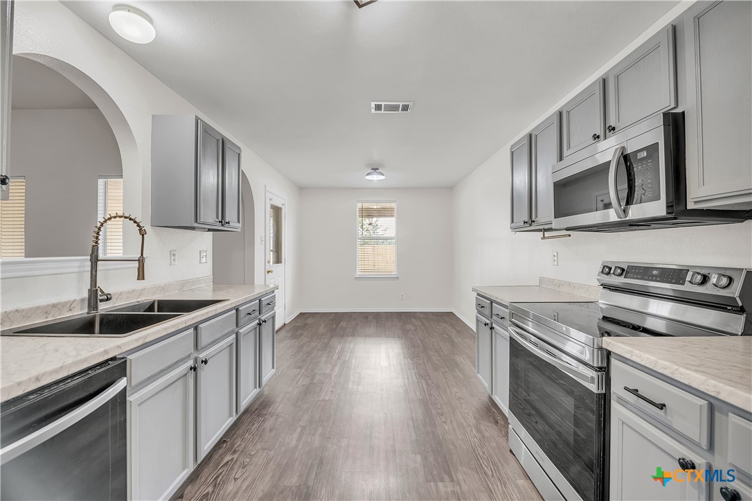 2903 Blue Ridge Drive Killeen, TX 76543 - Photo 12 of 32 a kitchen with stainless steel appliances granite countertop a sink dishwasher stove and microwave oven with wooden floor