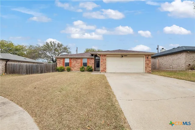 a front view of a house with a yard and wooden fence