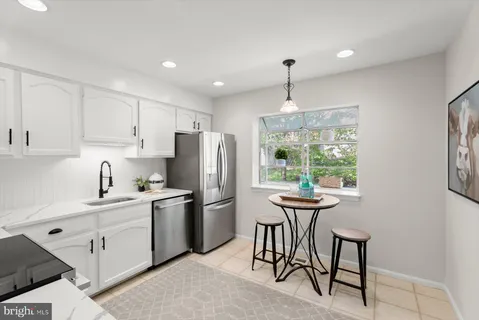 a kitchen with stainless steel appliances a dining table chairs stove refrigerator and cabinets