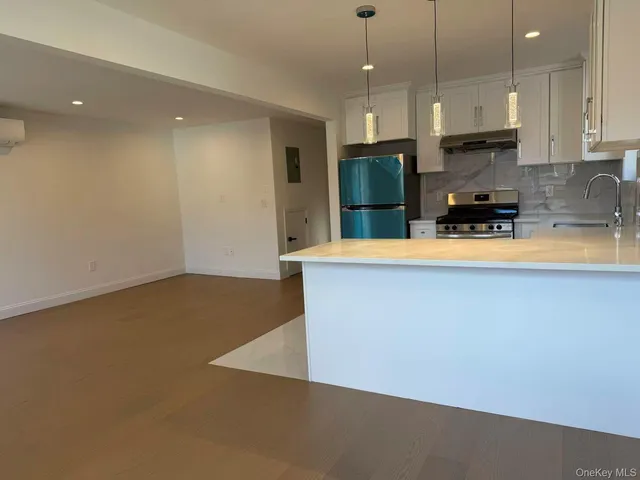 a large kitchen with stainless steel appliances a large counter top a stove and a refrigerator