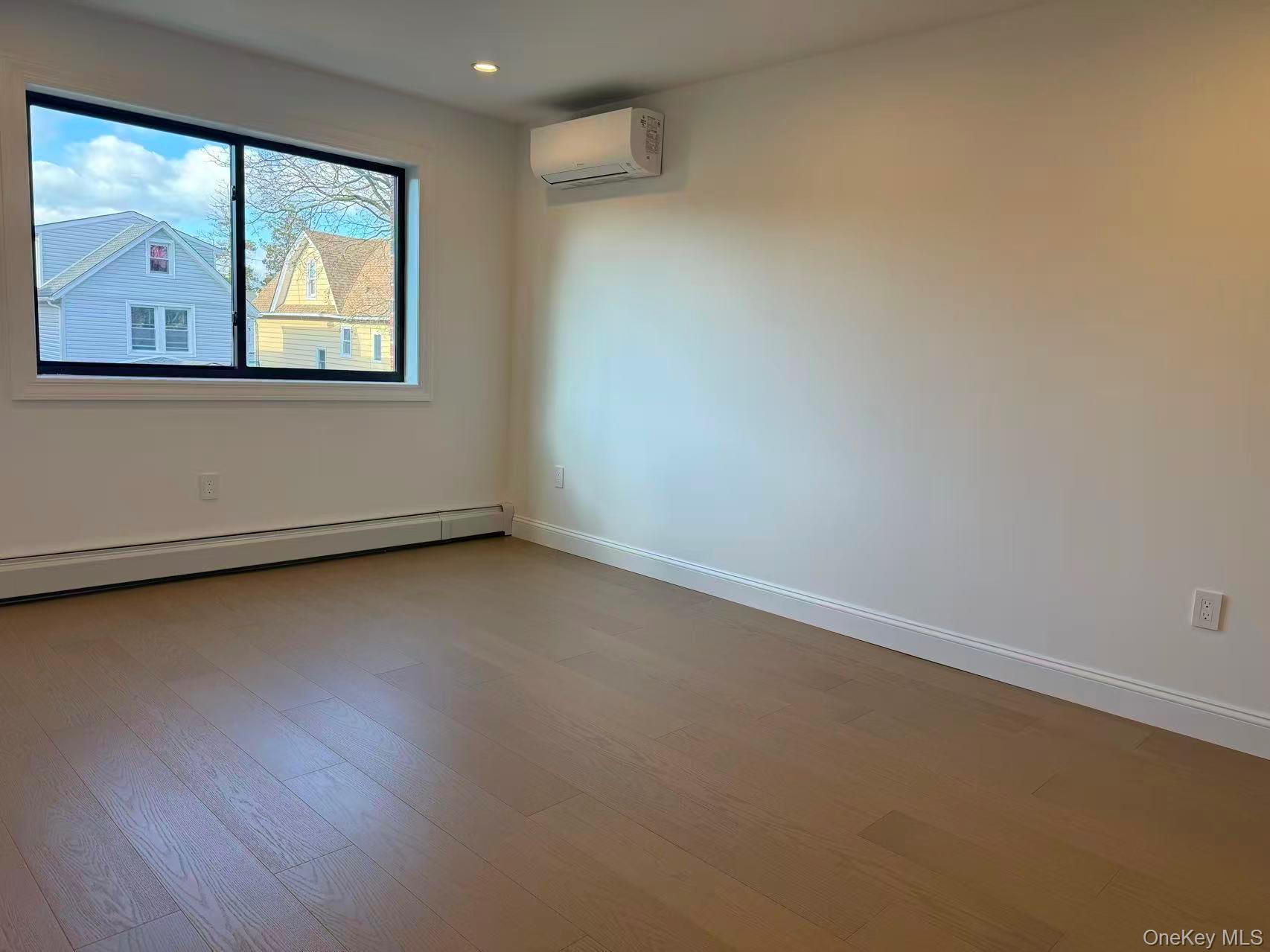 43-44 161 Street Queens, NY 11358 - Photo 5 of 12 Unfurnished room featuring wood finished floors, a wall unit AC, and a baseboard heating unit