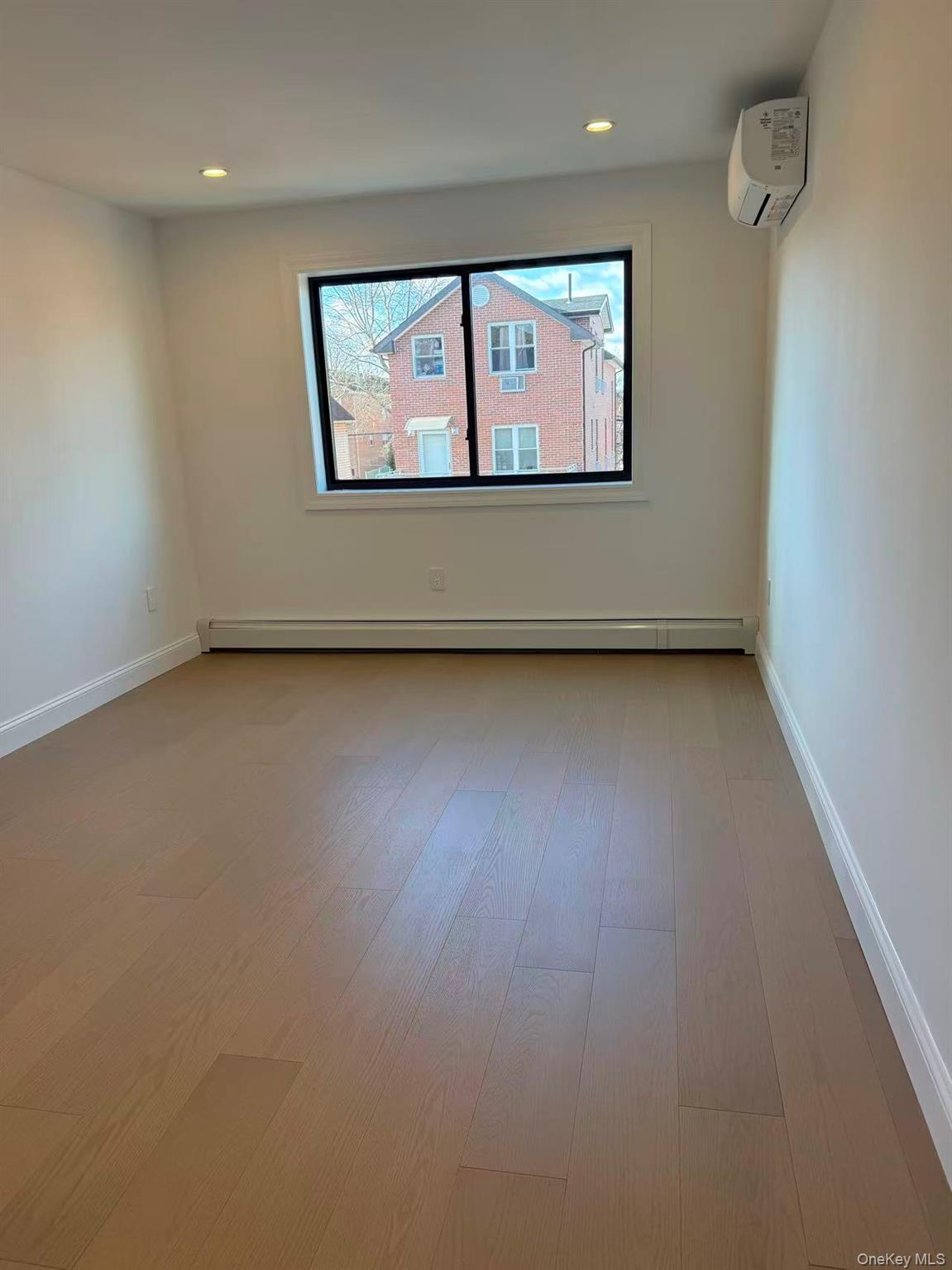 43-44 161 Street Queens, NY 11358 - Photo 6 of 12 Empty room with a wall mounted AC, a baseboard radiator, light wood-style flooring, and recessed lighting