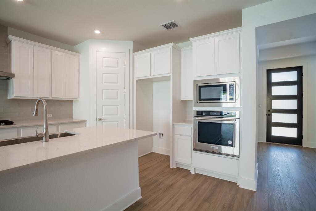 4612 Modena Bay Bend Leander, TX 78641 - Photo 13 of 34 Kitchen featuring appliances with stainless steel finishes, white cabinets, dark wood-style floors, and recessed lighting