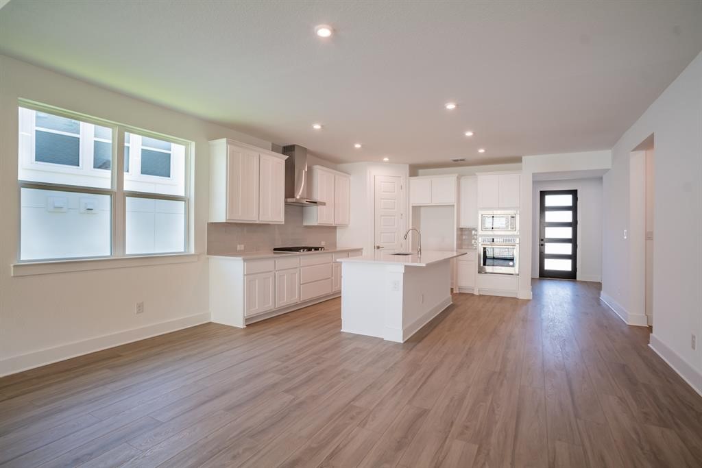 4612 Modena Bay Bend Leander, TX 78641 - Photo 15 of 34 Kitchen featuring white cabinets, stainless steel oven, a kitchen island with sink, recessed lighting, and wall chimney exhaust hood