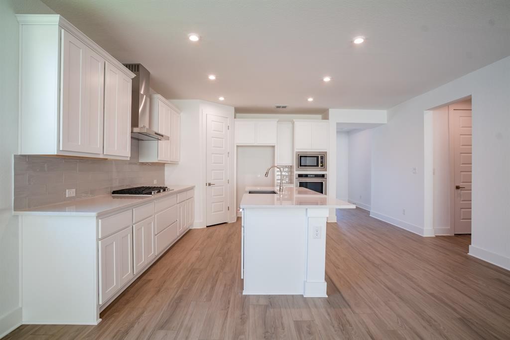 4612 Modena Bay Bend Leander, TX 78641 - Photo 16 of 34 Kitchen featuring tasteful backsplash, white cabinets, an island with sink, stainless steel appliances, and recessed lighting