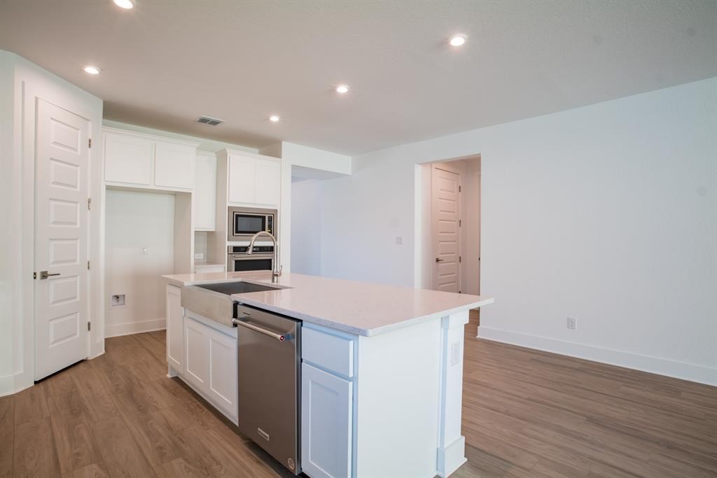 4612 Modena Bay Bend Leander, TX 78641 - Photo 17 of 34 Kitchen featuring white cabinetry, appliances with stainless steel finishes, light wood-style flooring, light stone counters, and recessed lighting