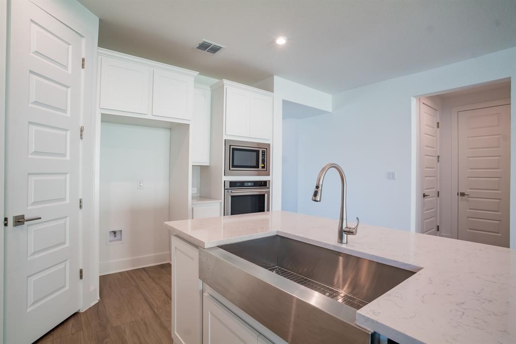 4612 Modena Bay Bend Leander, TX 78641 - Photo 18 of 34 Kitchen with white cabinetry, stainless steel appliances, light stone counters, light wood-style flooring, and recessed lighting